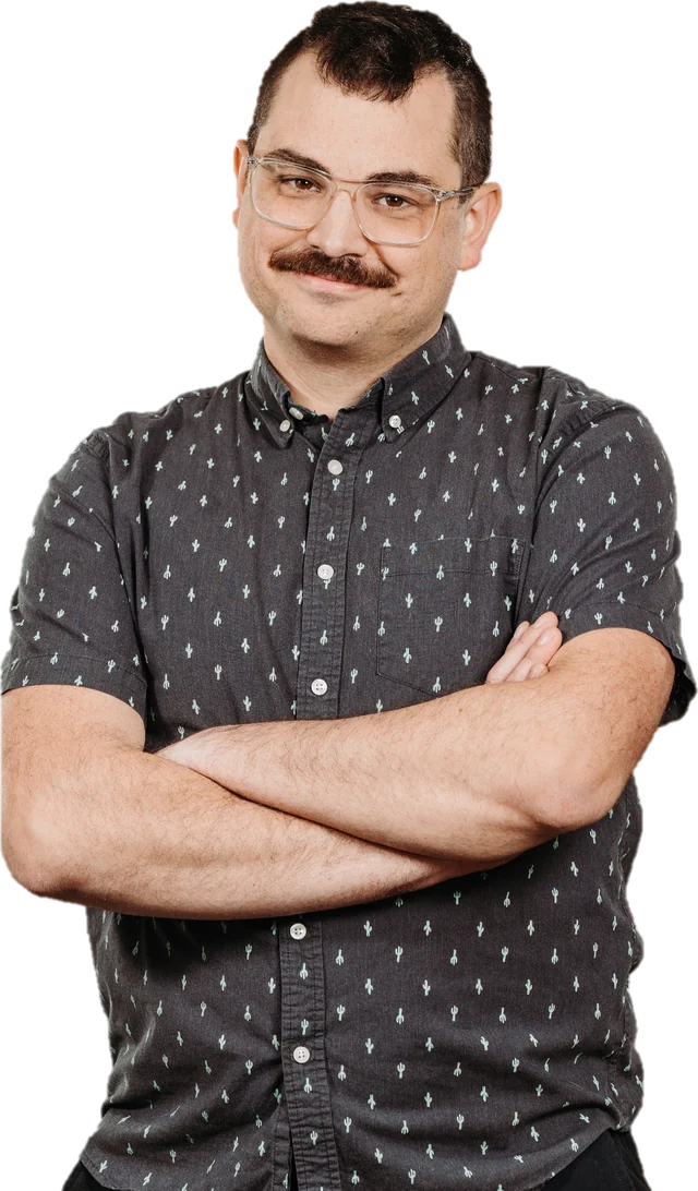 Stephen Eren with a small smile and his arms crossed, wearing glasses and a gray short-sleeve shirt with a small cactus pattern.