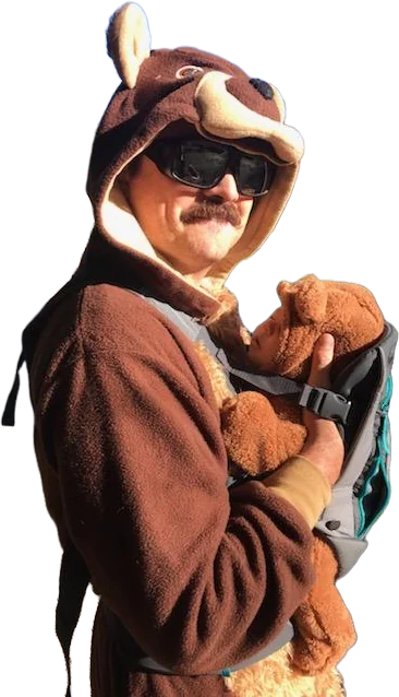 Stephen in a brown bear costume hoodie and sunglasses, holding his baby in a carrier, who is wearing a matching bear outfit.